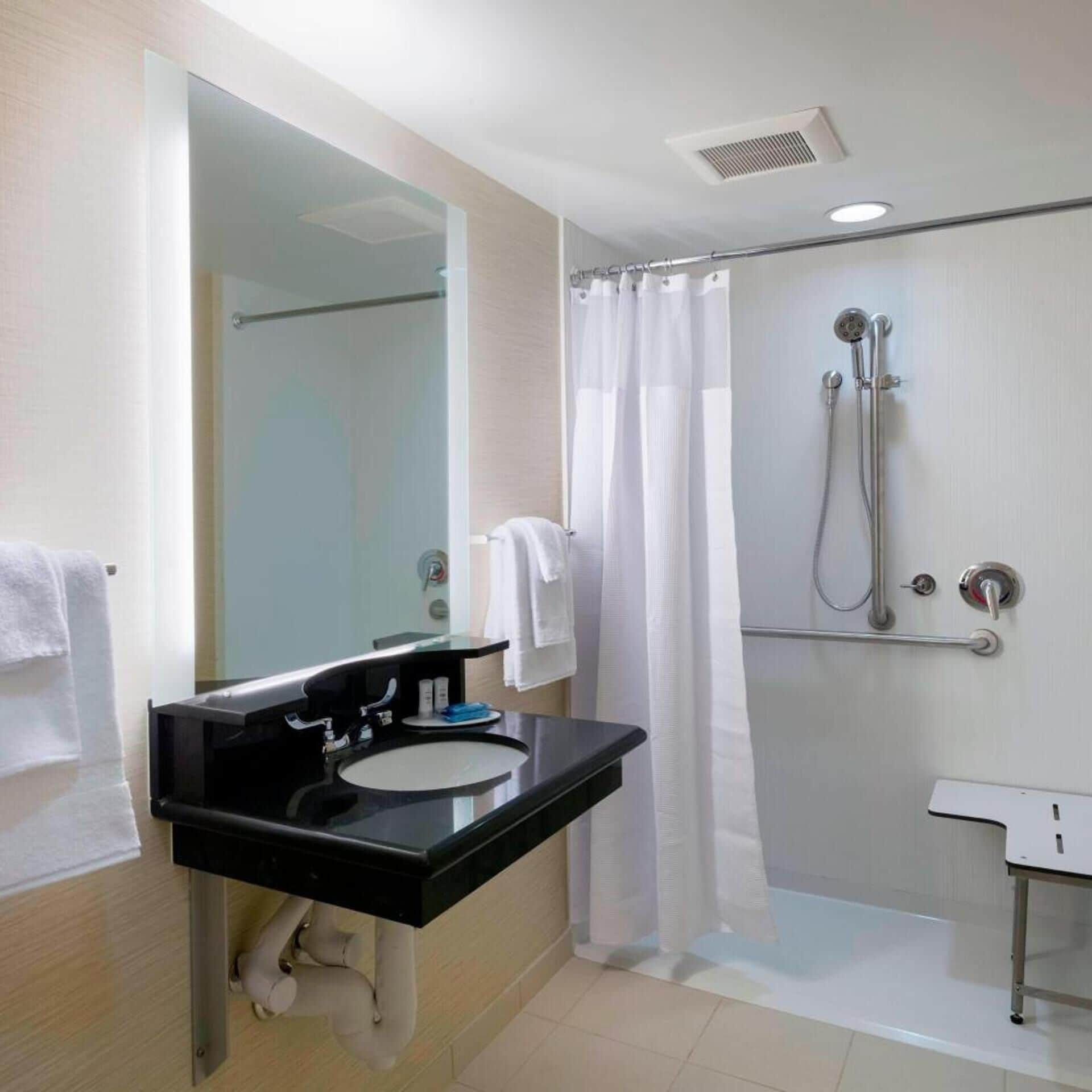 A bathroom with a black sink, a glass shower enclosure, and a white shower curtain.