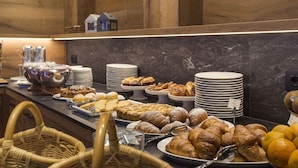 Un buffet proposant une variété de viennoiseries et de pâtisseries, notamment des croissants et du pain, présentés sur des assiettes et des plateaux de service.