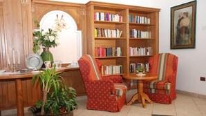 Un coin lecture confortable avec deux fauteuils, une bibliothèque en bois et une petite table.
