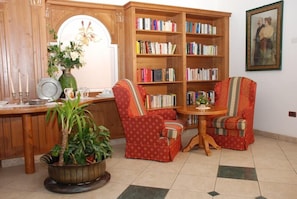 Un coin lecture confortable avec deux fauteuils, une bibliothèque en bois et une petite table.