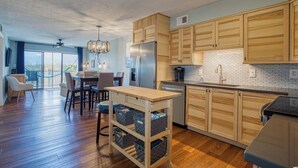 Eine moderne Küche mit Holzausstattung, einem Edelstahlkühlschrank und einem Essbereich mit Tisch und Stühlen.