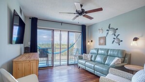 Ein geräumiges Wohnzimmer mit einer Ledersofa, einem Holztisch und einem Deckenventilator.