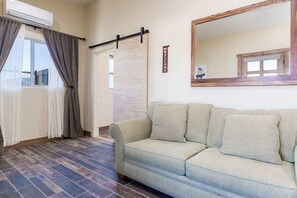 A room with a sofa, a sliding door, a mirror, and a 'WELCOME' sign.