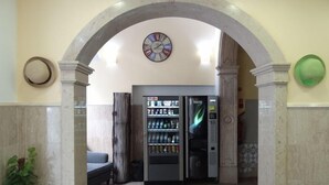 Un hall d’entrée avec un distributeur automatique, une horloge et un espace détente.