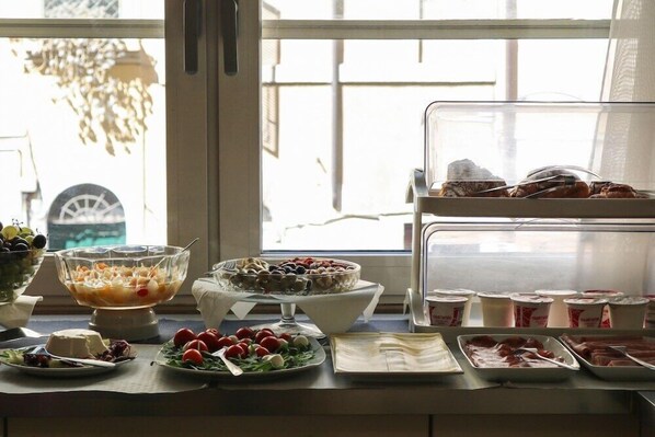 A buffet table with various food items and a window view.