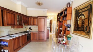 Una cocina con armarios de madera, encimera de mármol y mesa de comedor de vidrio con sillas.