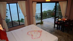 A bedroom with a bed, a view of the sea, and a balcony with a table and chairs. - Blue Hill Beach Resort (Ko Pha-ngan)