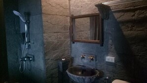 A stone-walled bathroom with a rustic sink, a shower, and a mirror. - Blue Hill Beach Resort (Ko Pha-ngan)