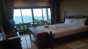 A hotel room with a large bed, a desk, and a view of the sea. - Blue Hill Beach Resort (Ko Pha-ngan)