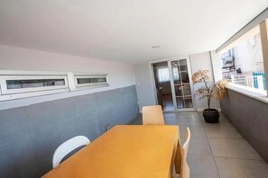 A modern room with a dining table, chairs, a potted plant, and a sliding glass door leading to a balcony. - Hotel Next2 (Istanbul)