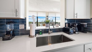 A modern kitchen with a large window, a built-in sink, and a coffee maker. - Stunning 2 Bedroom/ 2 Bath with Best Siesta Key Beach Views! (Siesta Key)