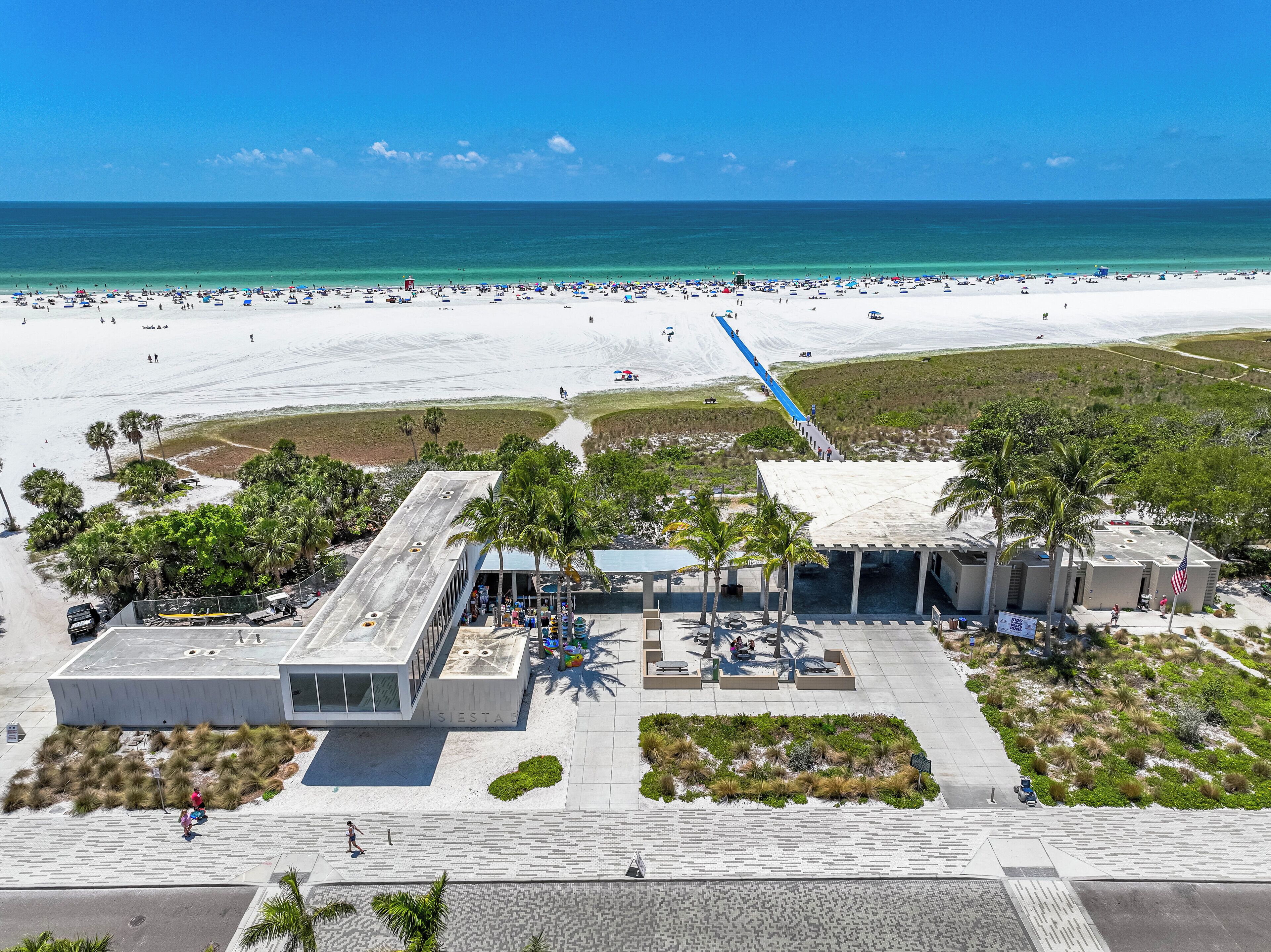 Un complexe hôtelier situé sur la plage, doté d’une vaste zone de sable, d’un parking et d’un bâtiment à toit plat.