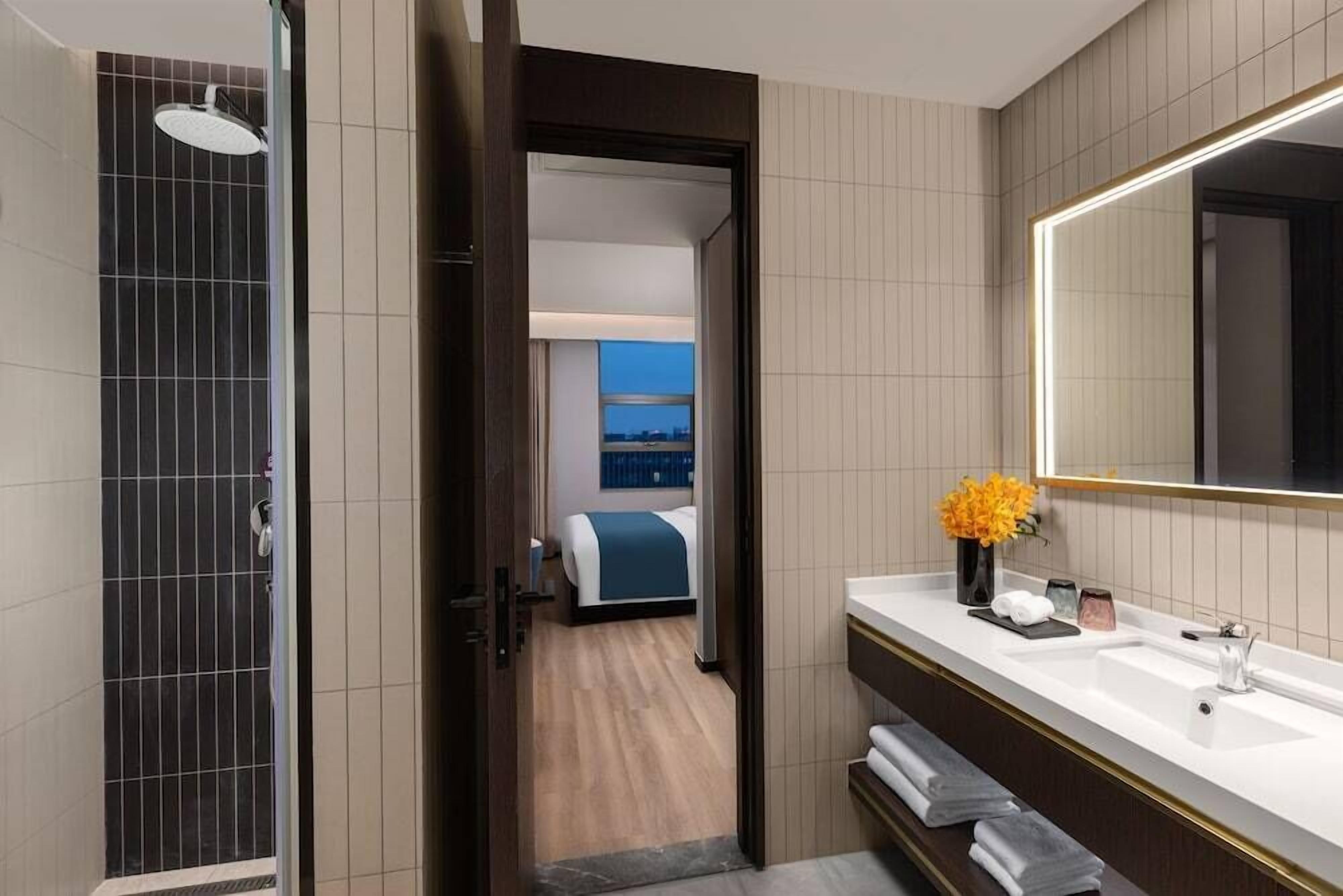 A modern bathroom with a shower, a large mirror, and a vanity with a sink.