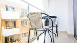 A balcony with two wicker chairs and a glass railing, overlooking a residential area. - Efi Hotel Apartments (Ayia Napa)