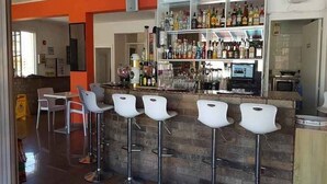 A bar area with a counter, bar stools, and shelves of bottles. - Efi Hotel Apartments (Ayia Napa)