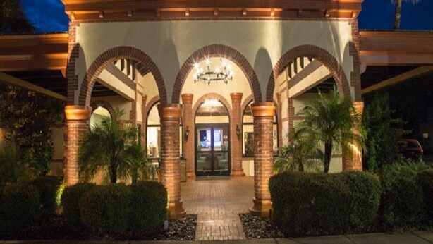 A hotel entrance with a covered patio, arched columns, and a chandelier. - The Flagler Inn (St. Augustine)