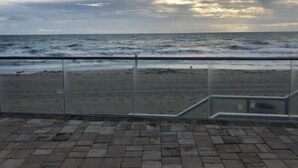 Blick auf einen Strand mit Glasgeländer und Ziegelboden.