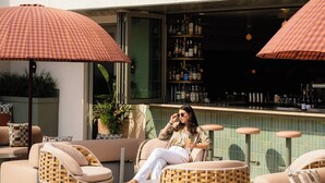 A poolside area with wicker lounge chairs, umbrellas, and a bar with bottles. - The Ryder Hotel (Charleston)