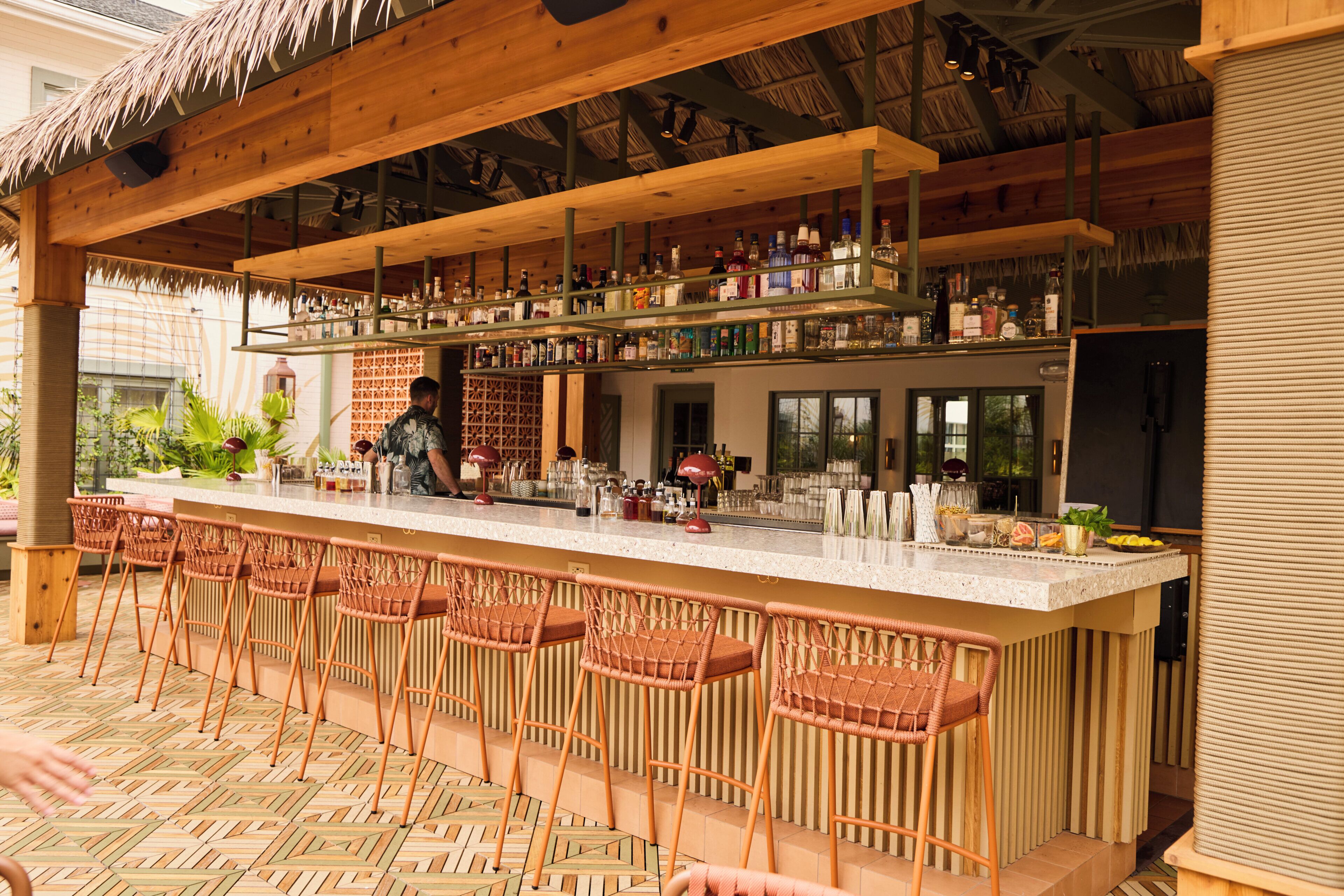A bar area with multiple stools and a bar counter stocked with various bottles.