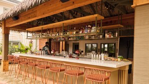 A bar area with multiple stools and a bar counter stocked with various bottles. - The Ryder Hotel (Charleston)