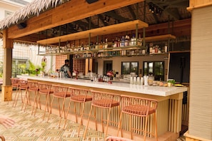 A bar area with multiple stools and a bar counter stocked with various bottles. - The Ryder Hotel (Charleston)