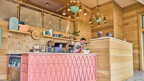 A coffee counter with a pink and gold design, a coffee machine, and a menu board. - The Ryder Hotel (Charleston)