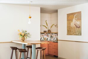 A kitchen with a wooden island, bar stools, a hanging light fixture, and a wall-mounted sink. - The Ryder Hotel (Charleston)