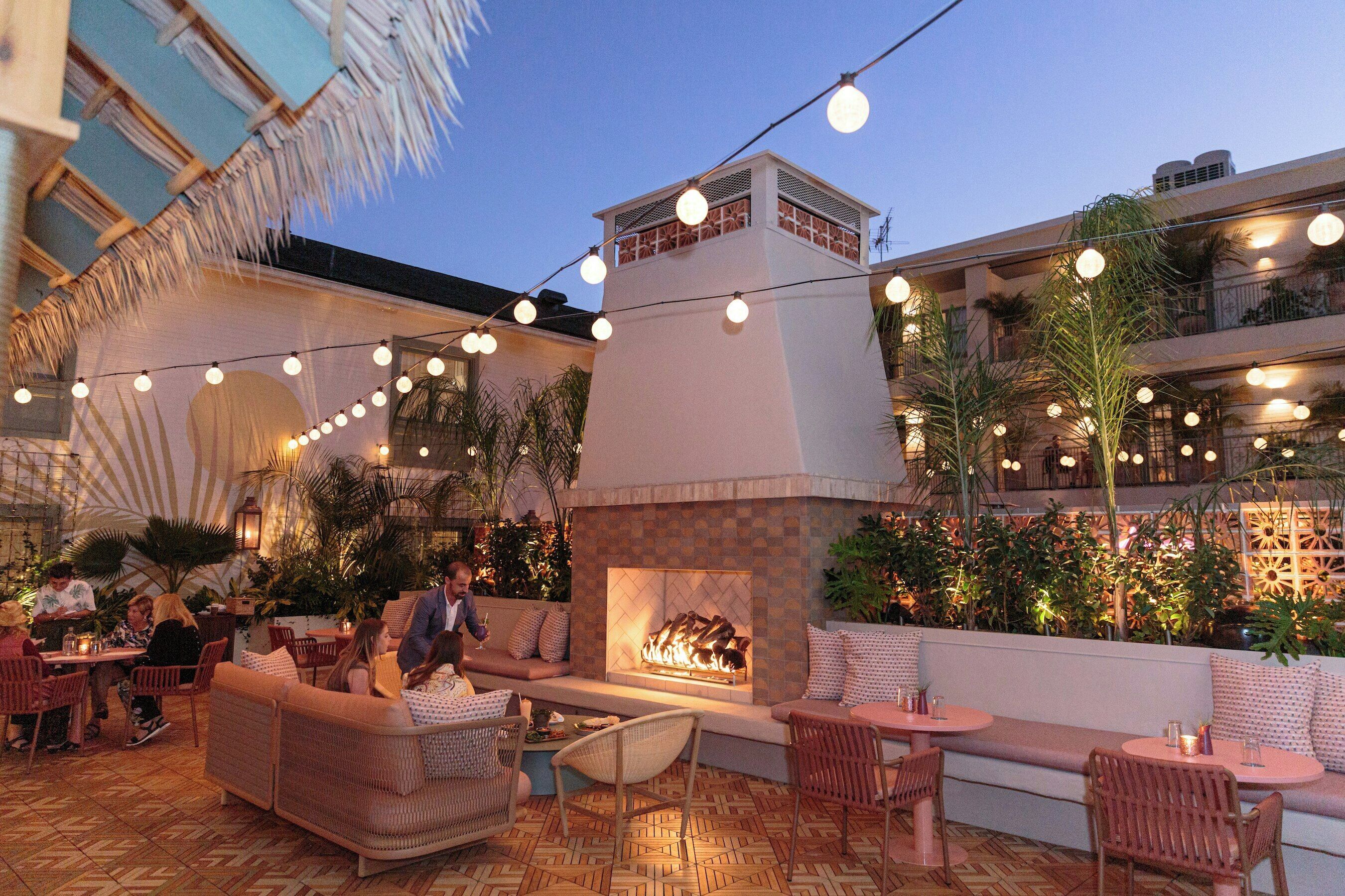 An outdoor seating area with wicker furniture, a fire pit, and string lights.