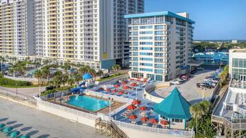 Um hotel com vários edifícios altos, uma piscina e um estacionamento.