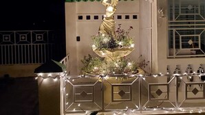 A decorative fountain with a statue, surrounded by a white railing with geometric patterns, set against a building with a green and white facade. - La Casita Verde in Cupey - Villa with Pool-Hot Tub and POWER GENERATOR (San Juan)