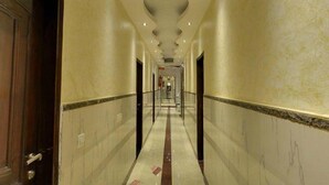 A long, narrow hallway with marble floors and walls, featuring a central column and doors on either side. - Hotel Emperor Palms (New Delhi)
