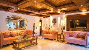 A spacious living room with two plush sofas, a coffee table, and a large mirror. - Hotel Emperor Palms (New Delhi)