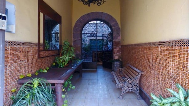Un patio cubierto con paredes de baldosas, un banco y plantas en macetas.