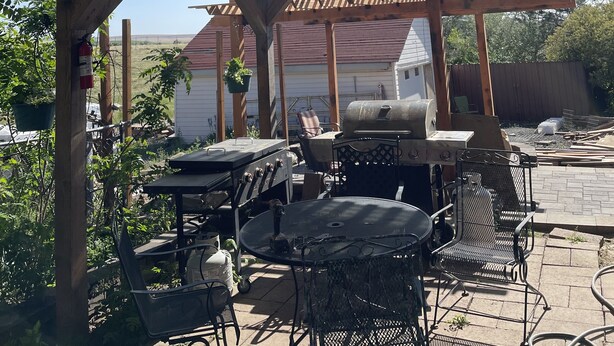 Eine Außenpatio mit Pergola, Grillplatz und Sitzgelegenheiten.