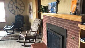 Ein Wohnzimmer mit Kamin, einer Uhr und einem Bücherregal.