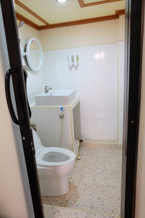 Bathroom features a toilet, sink, and mirror, with tiled walls and a patterned tile floor.