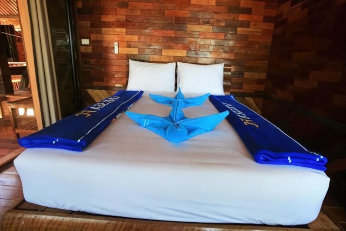 A bed with a white mattress and blue headboards, set against a brick wall.