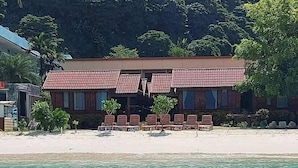 A beachfront building with a tiled roof, multiple windows, and a row of outdoor seating. - Phi Phi Sand Sea View Resort (Ko Phi Phi)