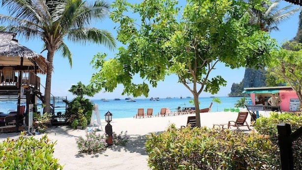A beachside resort with a thatched-roof structure, lounge chairs, and a view of the sea. - Phi Phi Sand Sea View Resort (Ko Phi Phi)