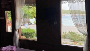 A room with a bed, two windows with curtains, and a view of a beach. - Phi Phi Sand Sea View Resort (Ko Phi Phi)