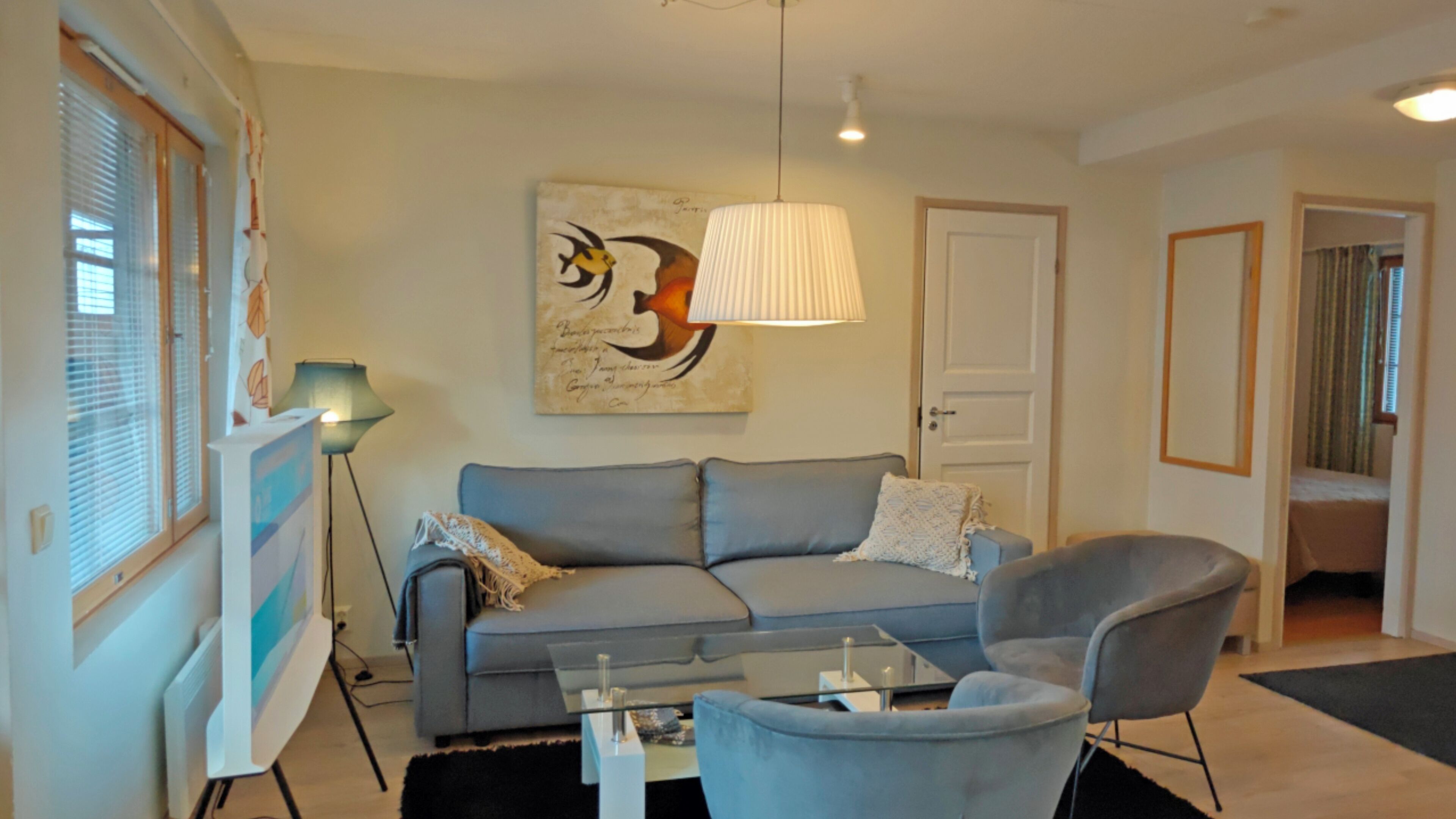 A living room with a sofa, a chair, a table, a lamp, and a wall art piece.