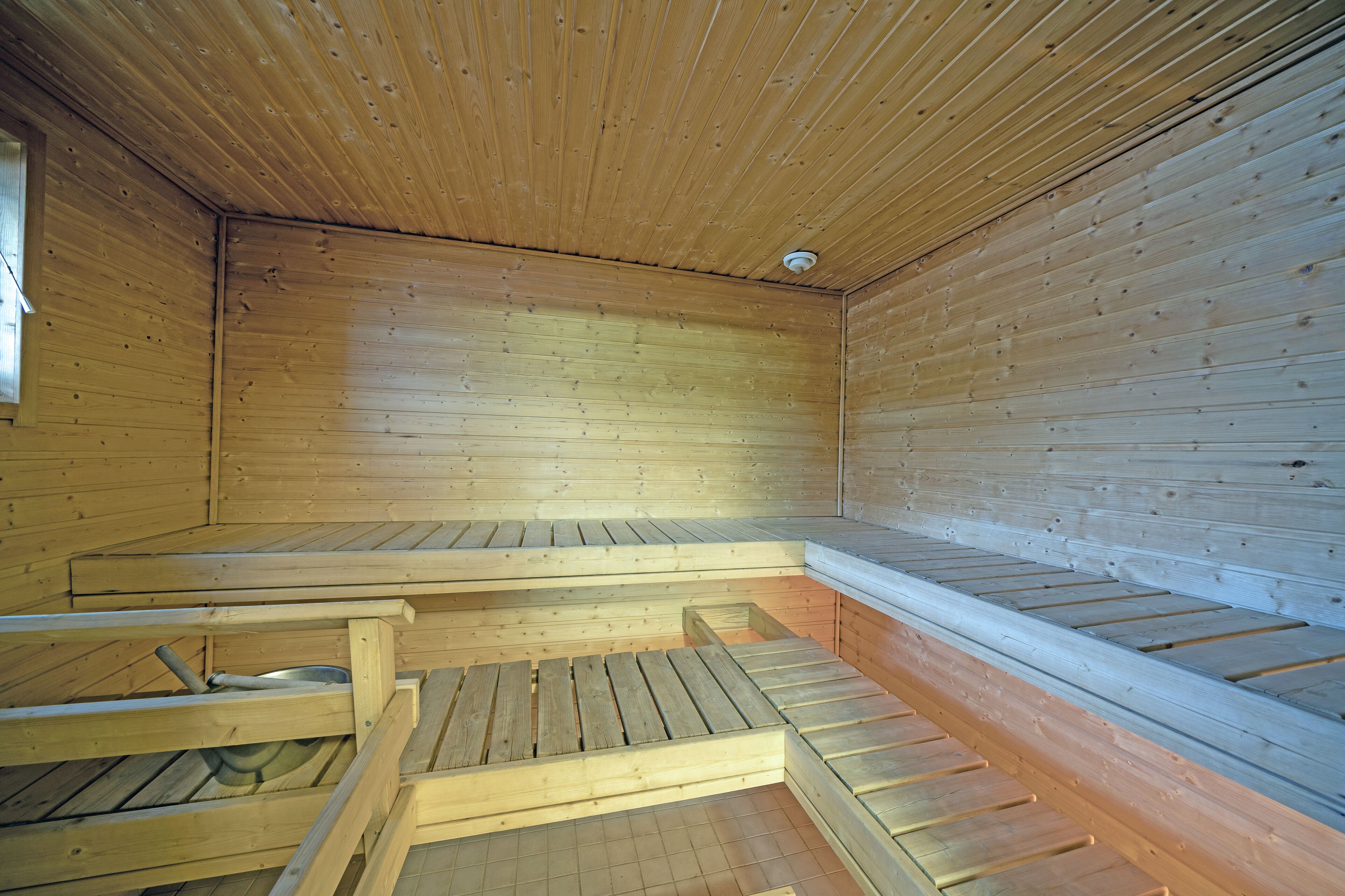 Una sala de sauna con bancos de madera y techo inclinado.