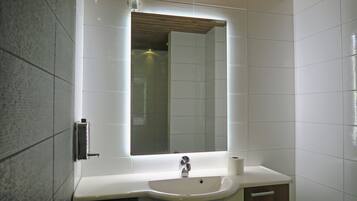 A bathroom with a white sink, a mirror, and a toilet.