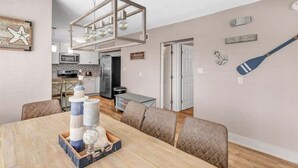 A dining area with a wooden table, cushioned chairs, and a decorative centerpiece. - Reel Deal ~ Private Pool Home, 76' Dock (Marathon)