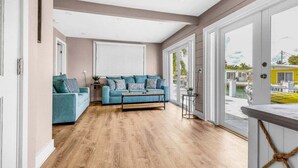 A spacious living room with a blue sofa, a coffee table, and a view of the outside. - Reel Deal ~ Private Pool Home, 76' Dock (Marathon)