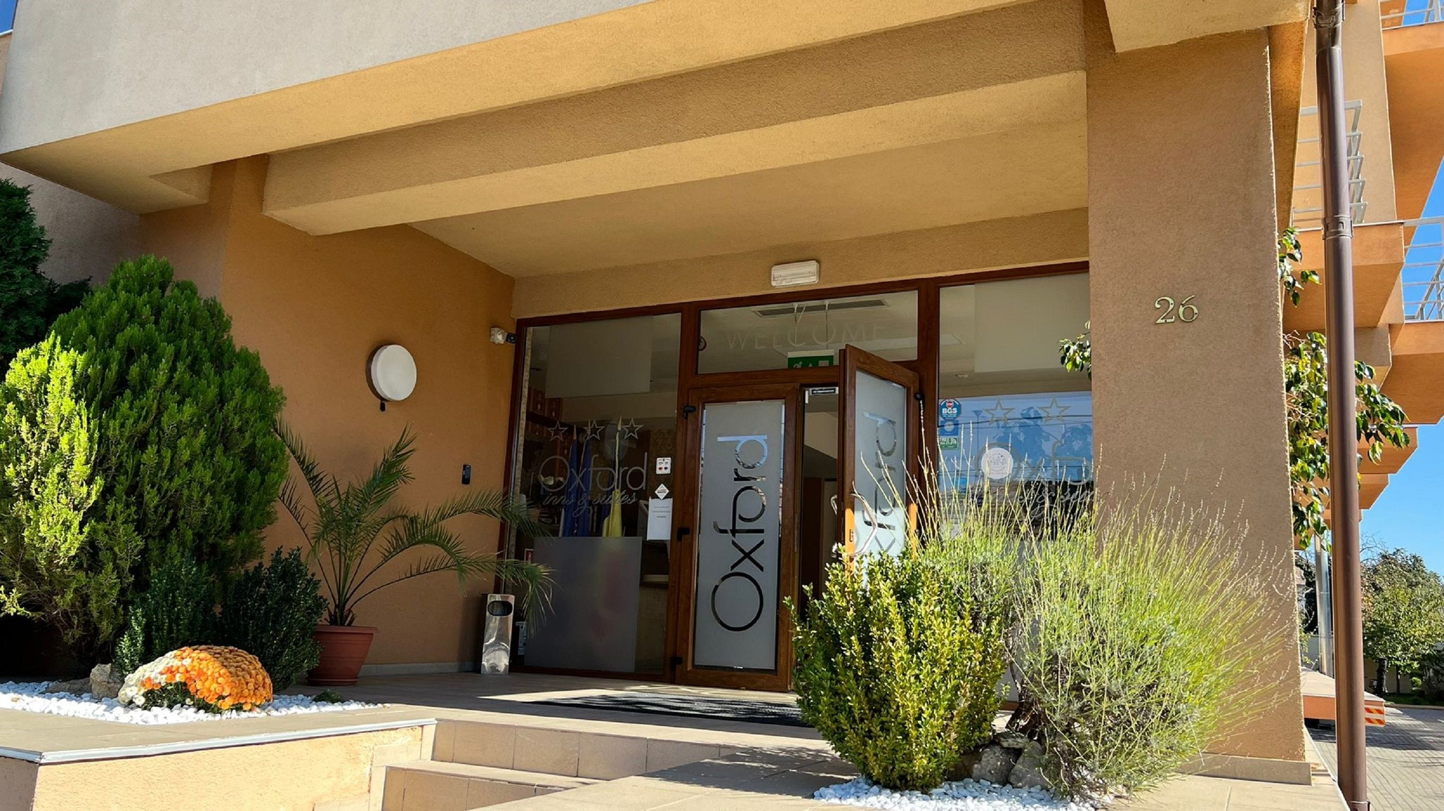A hotel entrance with a glass door, a sign reading "Oxford Inn," and a number "26" on the building.