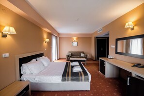 Una habitación de hotel con cama, escritorio, sillón y sofá.
