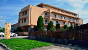 A multi-story building with a beige facade, a sign with stars, and a gated entrance. - Hotel Oxford Inns & Suites (Timisoara)