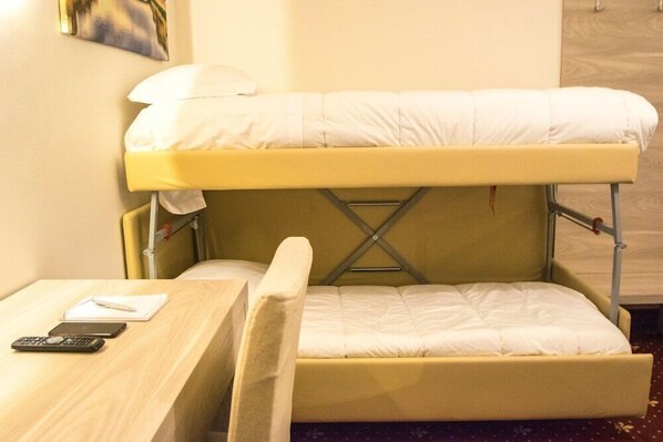 Un lit superposé avec un bureau et une chaise, une télécommande et un stylo sur le bureau.