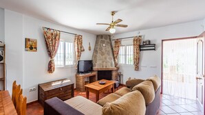 A living room with a fireplace, sofa, television, and wooden furniture. - Chalet Algar by Ruralidays (Cádiz)